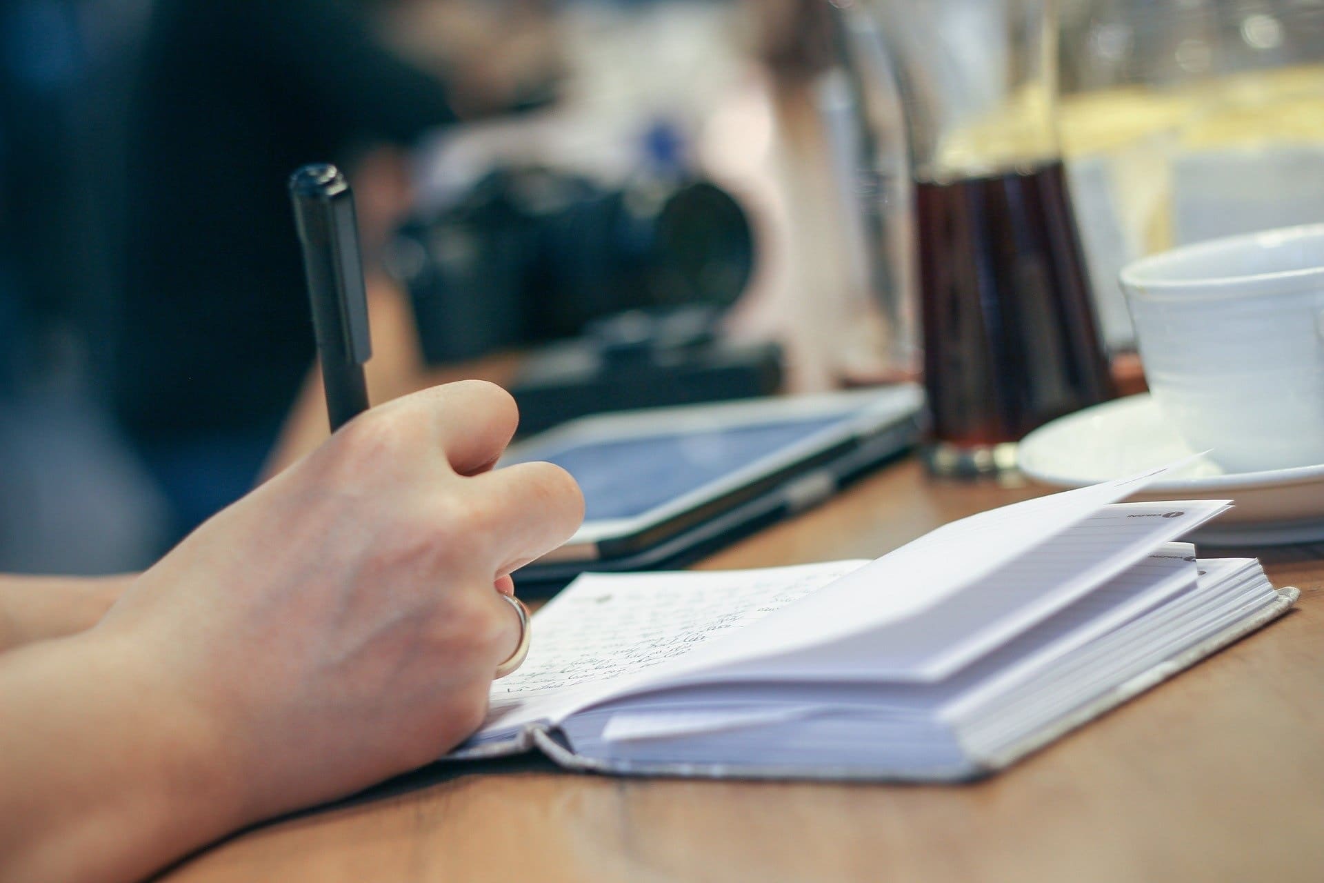 FORMATION DÉCLARANT EN DOUANE personne écrivant au stylo dans un cahier ouvert posé sur un bureau